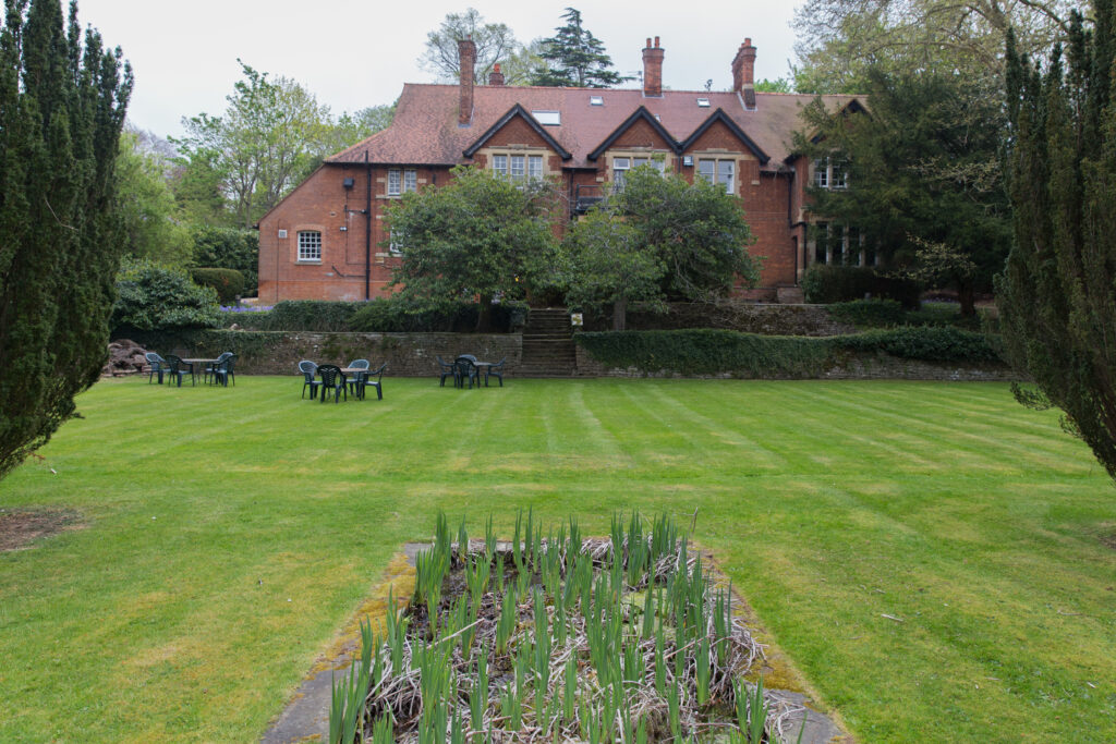 large grass area with tables and chairs with large house in background